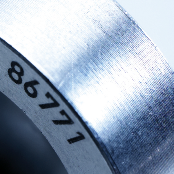 Close-up of a laser-marked metal component displaying the number "86771," highlighting precision in industrial marking applications for automotive parts and machinery.