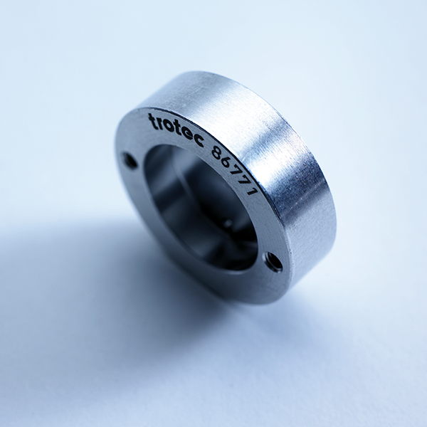 Metal component with engraved text "trotec 86771," showcasing precision laser marking technology relevant to electrical and industrial applications.